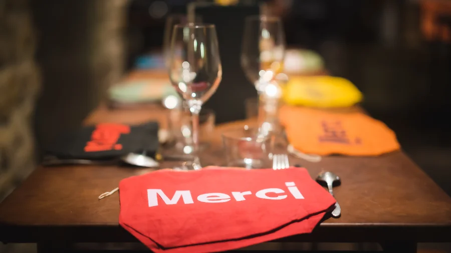 Photographe événementiel - Couverture d'une table de gala élégante avec des pochettes rouges "Merci"
